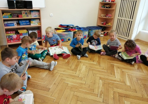 Dzieci siedzą w kole i oglądają książeczki